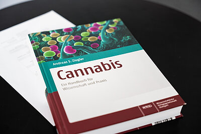 Ein Buches mit dem Titel "Cannabis" liegt auf einem Tisch