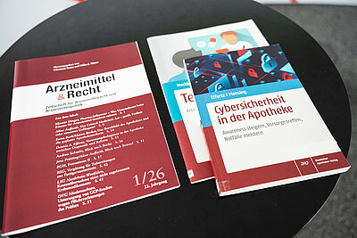 Foto der Zeitschrift "Apotheke & Recht" und daneben das Buch "Cybersicherheit in der Apotheke"