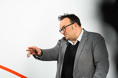Dr. Stephan Walch im Studio mit dem Finger auf etwas zeigend
