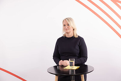 Christiane Müller ist auf dem Bild hinter einem Stehtisch vor weißem Hintergrund zu sehen.